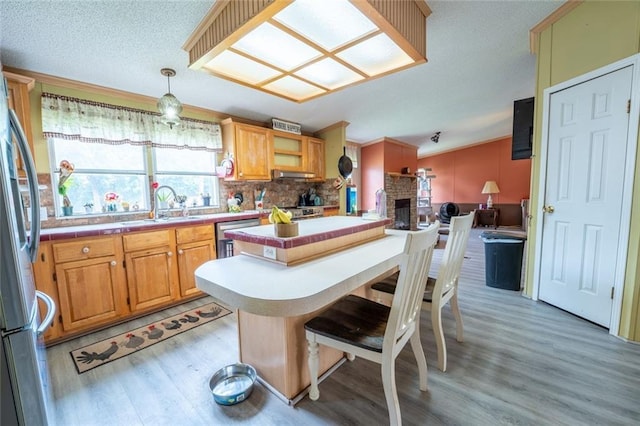 735 Hale Rd, Maysville, GA 30558 - kitchen featuring light wood-style flooring, stainless steel appliances, a stone fireplace, decorative backsplash, and a kitchen island