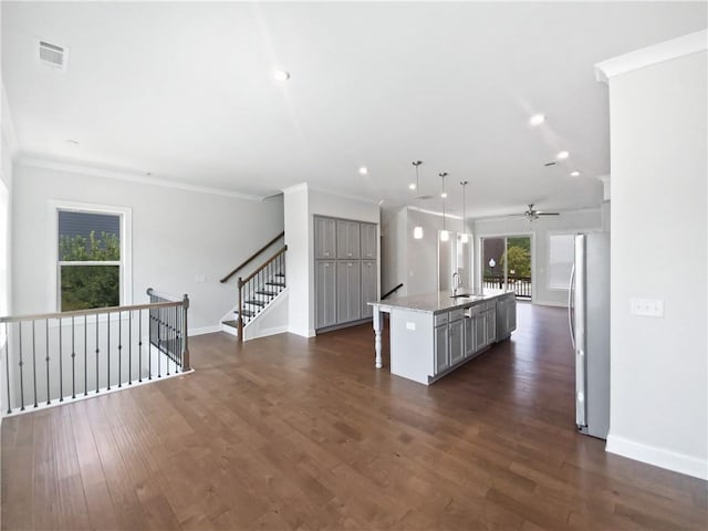 kitchen with gray cabinets, pendant lighting, stainless steel fridge, an island with sink, and dark hardwood / wood-style floors