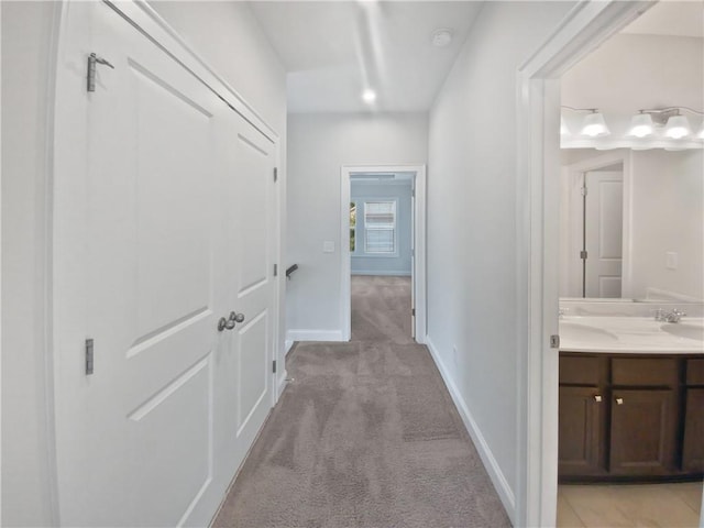 hall featuring light colored carpet and sink