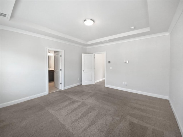 unfurnished bedroom featuring a raised ceiling, connected bathroom, and carpet