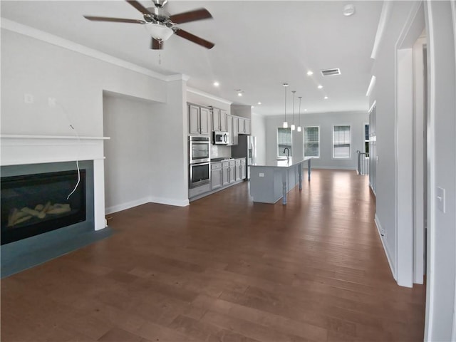 unfurnished living room featuring crown molding, dark wood-type flooring, ceiling fan, and sink