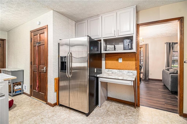 5843 Foxfield Trl, Rex, GA 30273 - kitchen featuring stainless steel fridge with ice dispenser, a textured ceiling, light countertops, white cabinetry, and baseboards