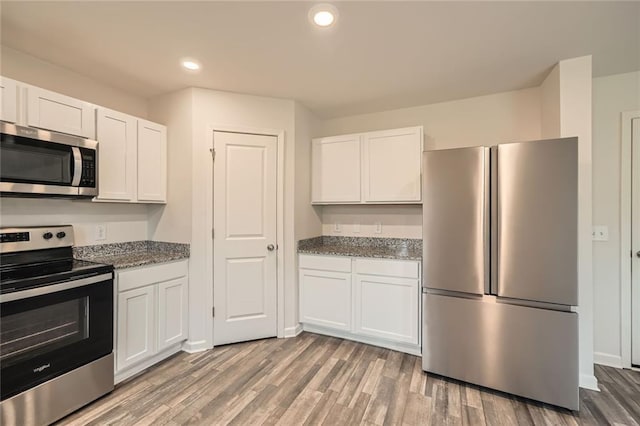 kitchen with stainless steel appliances, white cabinetry, and wood finished floors