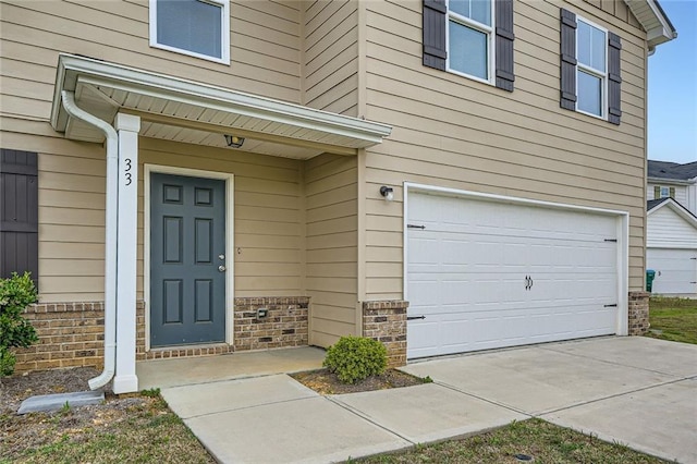 doorway to property featuring brick siding and a garage