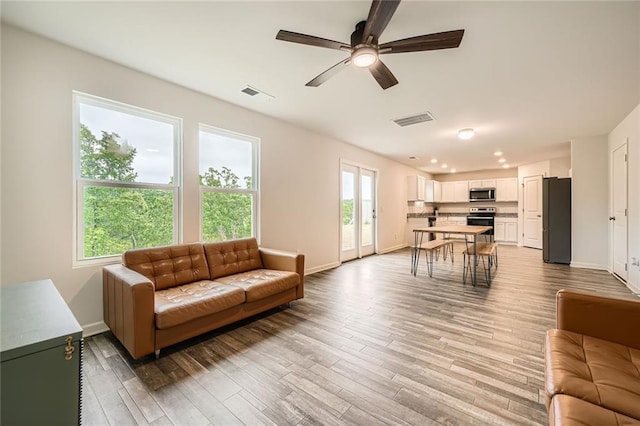living room with baseboards, ceiling fan, and visible vents