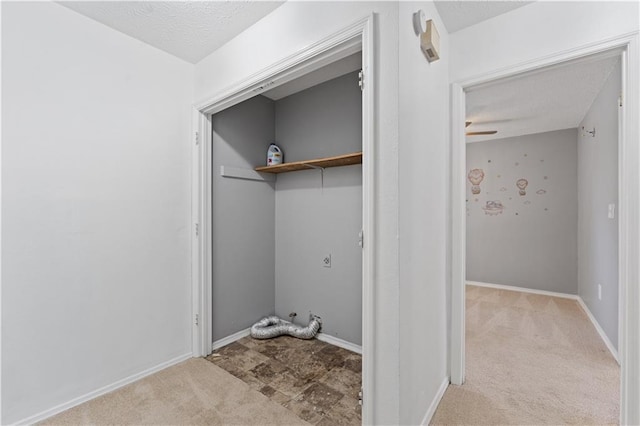 laundry room featuring light colored carpet and a textured ceiling