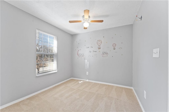 empty room with ceiling fan, light colored carpet, and a textured ceiling