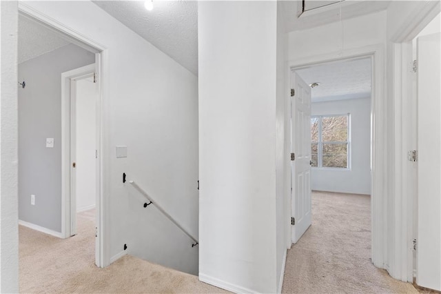 corridor with light colored carpet and a textured ceiling