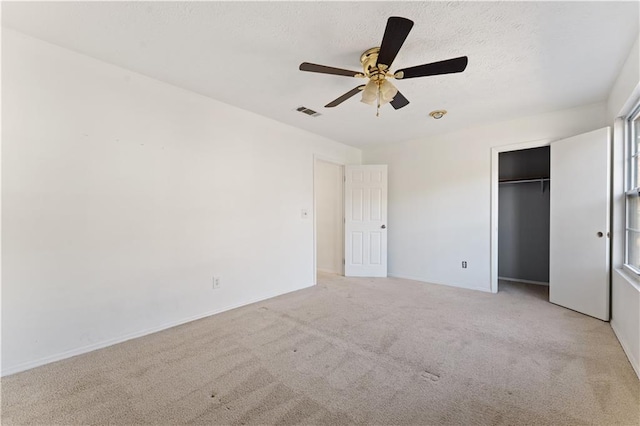 unfurnished bedroom featuring ceiling fan, a closet, light carpet, and a textured ceiling