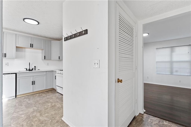 kitchen featuring sink, white appliances, and a textured ceiling