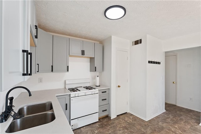 kitchen with gray cabinets, sink, white range with gas stovetop, and a textured ceiling