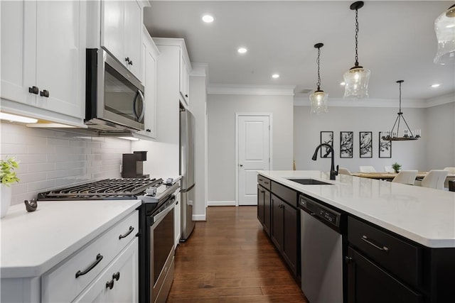 kitchen with white cabinetry, stainless steel appliances, sink, and a kitchen island with sink