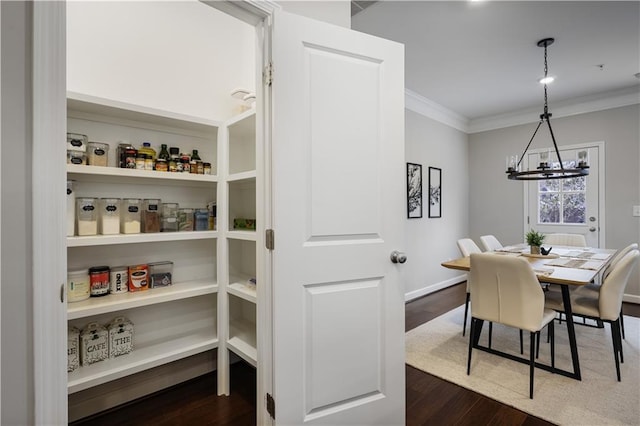 dining area featuring crown molding, dark wood-type flooring, and a chandelier