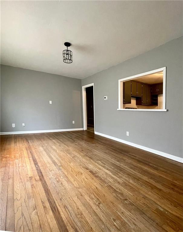 unfurnished living room with a chandelier and wood-type flooring