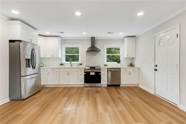 kitchen with white cabinets, wall chimney exhaust hood, stainless steel appliances, and ornamental molding