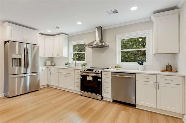 kitchen featuring white cabinets, wall chimney range hood, and appliances with stainless steel finishes