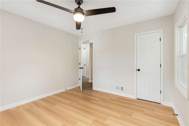 unfurnished bedroom featuring ceiling fan, multiple windows, and light hardwood / wood-style flooring