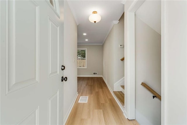 corridor with light hardwood / wood-style floors and ornamental molding