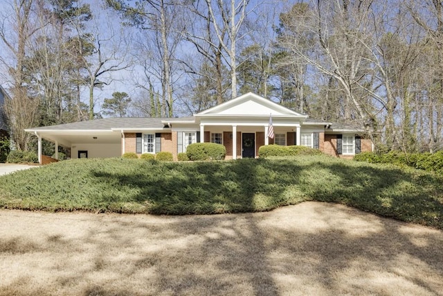 greek revival house with an attached carport, concrete driveway, and brick siding