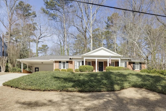 greek revival inspired property with a carport, driveway, and brick siding