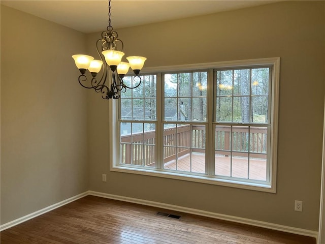 unfurnished dining area with an inviting chandelier, plenty of natural light, and hardwood / wood-style floors