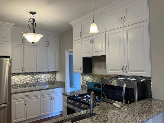 kitchen with pendant lighting, appliances with stainless steel finishes, tasteful backsplash, and white cabinets