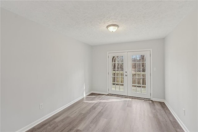 spare room featuring hardwood / wood-style floors, a textured ceiling, and french doors