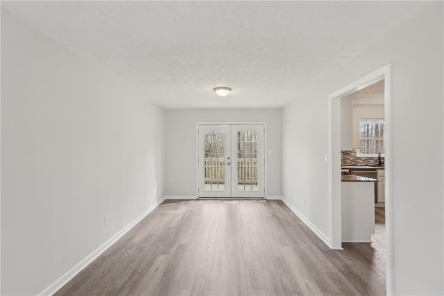 spare room featuring wood-type flooring, sink, a textured ceiling, and french doors