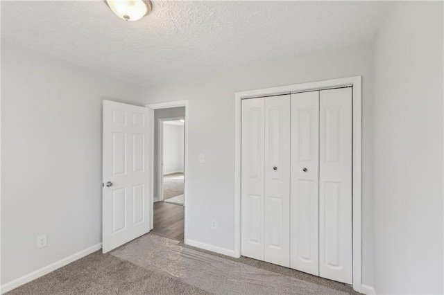 unfurnished bedroom featuring light colored carpet, a textured ceiling, and a closet