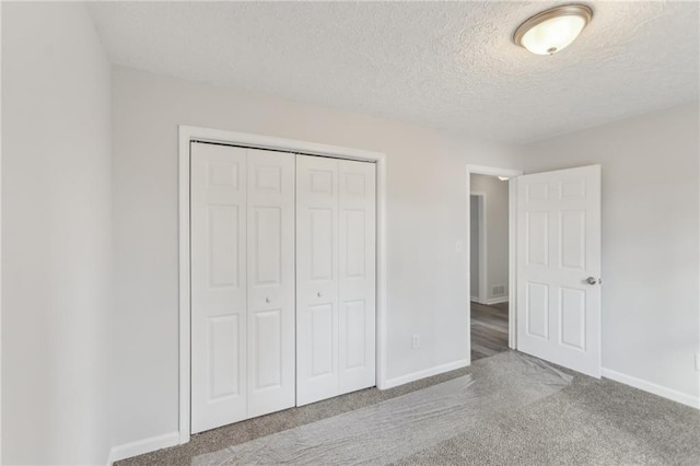 unfurnished bedroom with carpet floors, a textured ceiling, and a closet