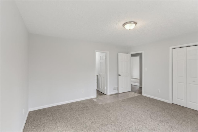 unfurnished bedroom featuring a closet, a textured ceiling, and carpet