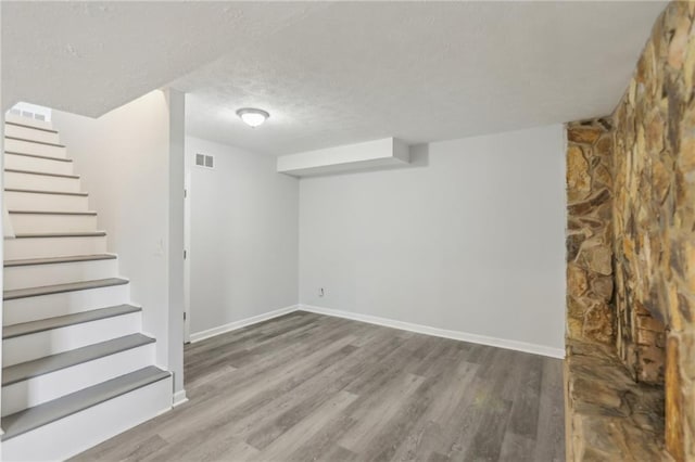 basement featuring wood-type flooring and a textured ceiling