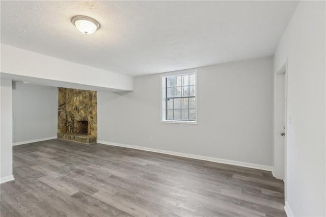 basement featuring wood-type flooring and a stone fireplace