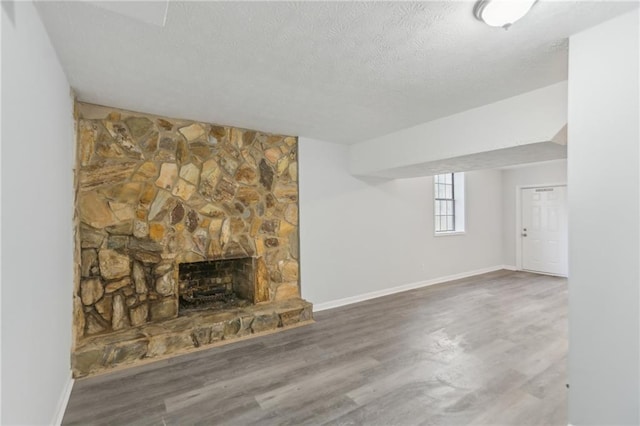 unfurnished living room with hardwood / wood-style flooring, a textured ceiling, and a fireplace