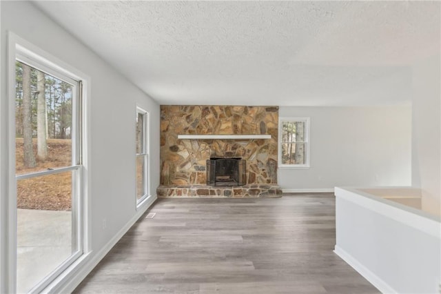 unfurnished living room featuring a healthy amount of sunlight, hardwood / wood-style floors, and a textured ceiling