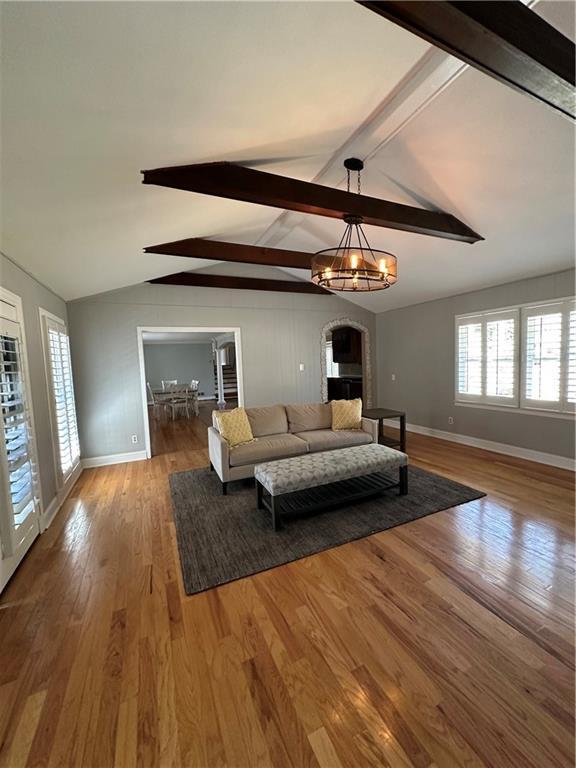 living area with lofted ceiling with beams, baseboards, and wood finished floors