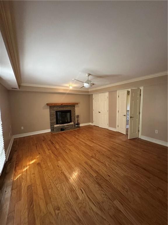 unfurnished living room with ceiling fan, baseboards, a fireplace with raised hearth, and wood finished floors