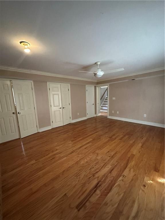 unfurnished living room with ornamental molding, baseboards, and wood finished floors