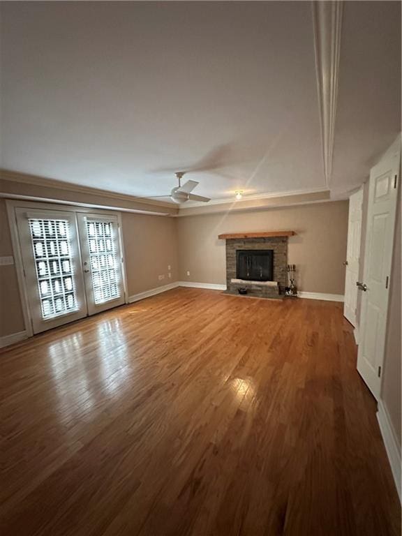 unfurnished living room featuring baseboards, ceiling fan, ornamental molding, a fireplace, and wood finished floors