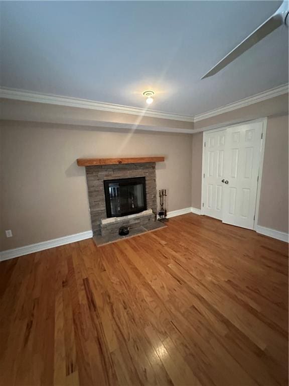 unfurnished living room featuring ornamental molding, a fireplace, baseboards, and wood finished floors