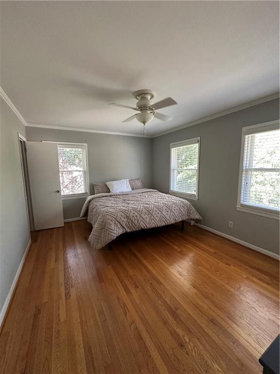 unfurnished bedroom featuring multiple windows, wood finished floors, and ornamental molding