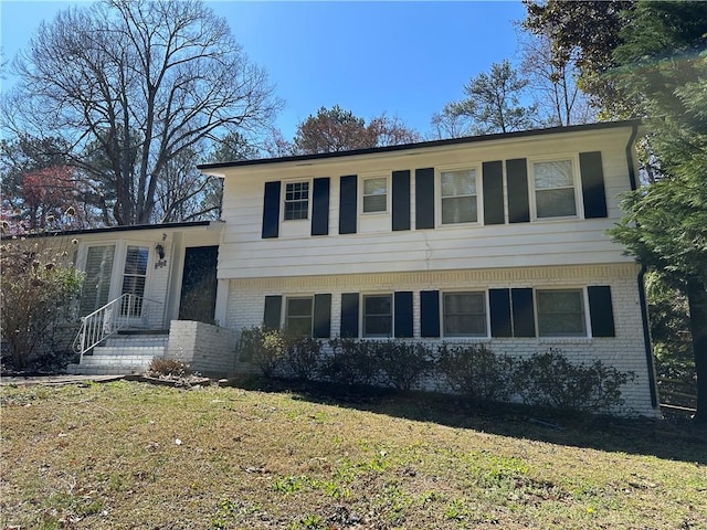 split level home with a front yard and brick siding