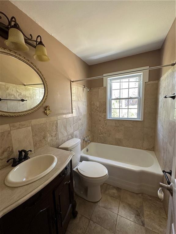 bathroom with tile patterned floors, toilet, shower / washtub combination, tile walls, and vanity