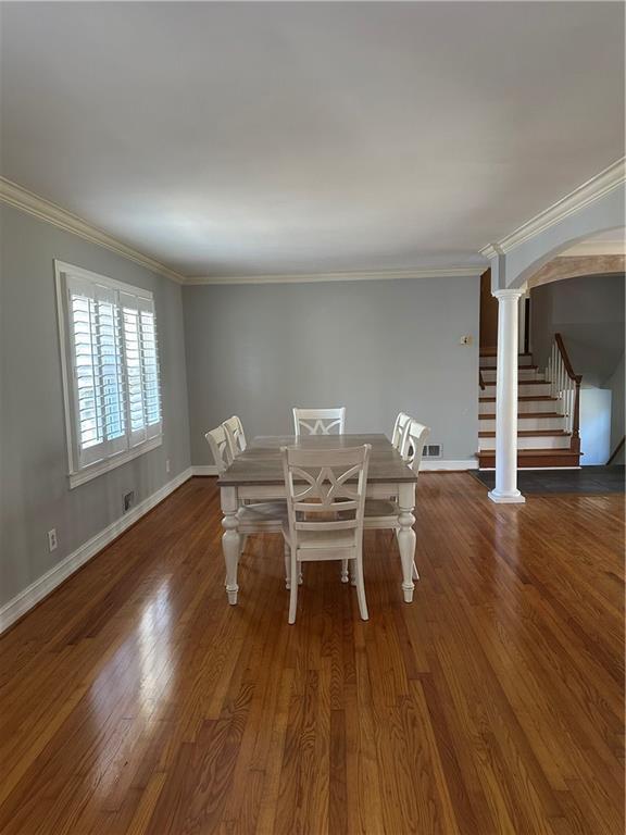 unfurnished dining area featuring arched walkways, baseboards, and wood finished floors