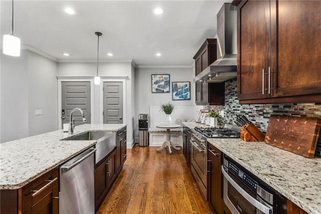 kitchen with pendant lighting, stainless steel appliances, wall chimney range hood, backsplash, and sink