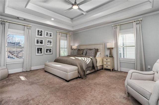 carpeted bedroom with crown molding, ceiling fan, a tray ceiling, and multiple windows