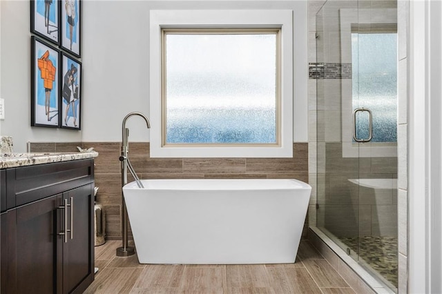 bathroom with tile walls, separate shower and tub, and vanity