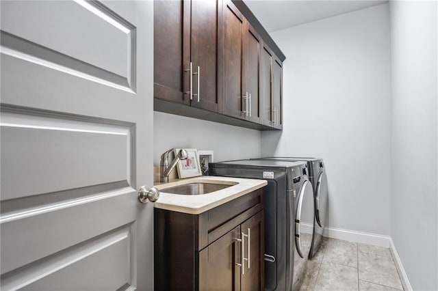 washroom featuring sink, light tile patterned flooring, washer and dryer, and cabinets