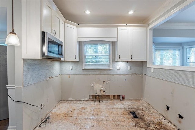 402 John Tate Rd NW, Acworth, GA 30102 - kitchen featuring stainless steel microwave, backsplash, white cabinets, ornamental molding, and hanging light fixtures