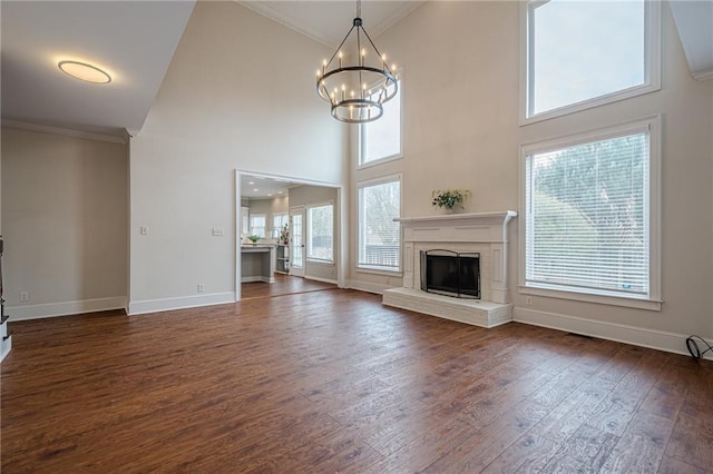 unfurnished living room featuring a high ceiling, dark hardwood / wood-style flooring, a wealth of natural light, and an inviting chandelier